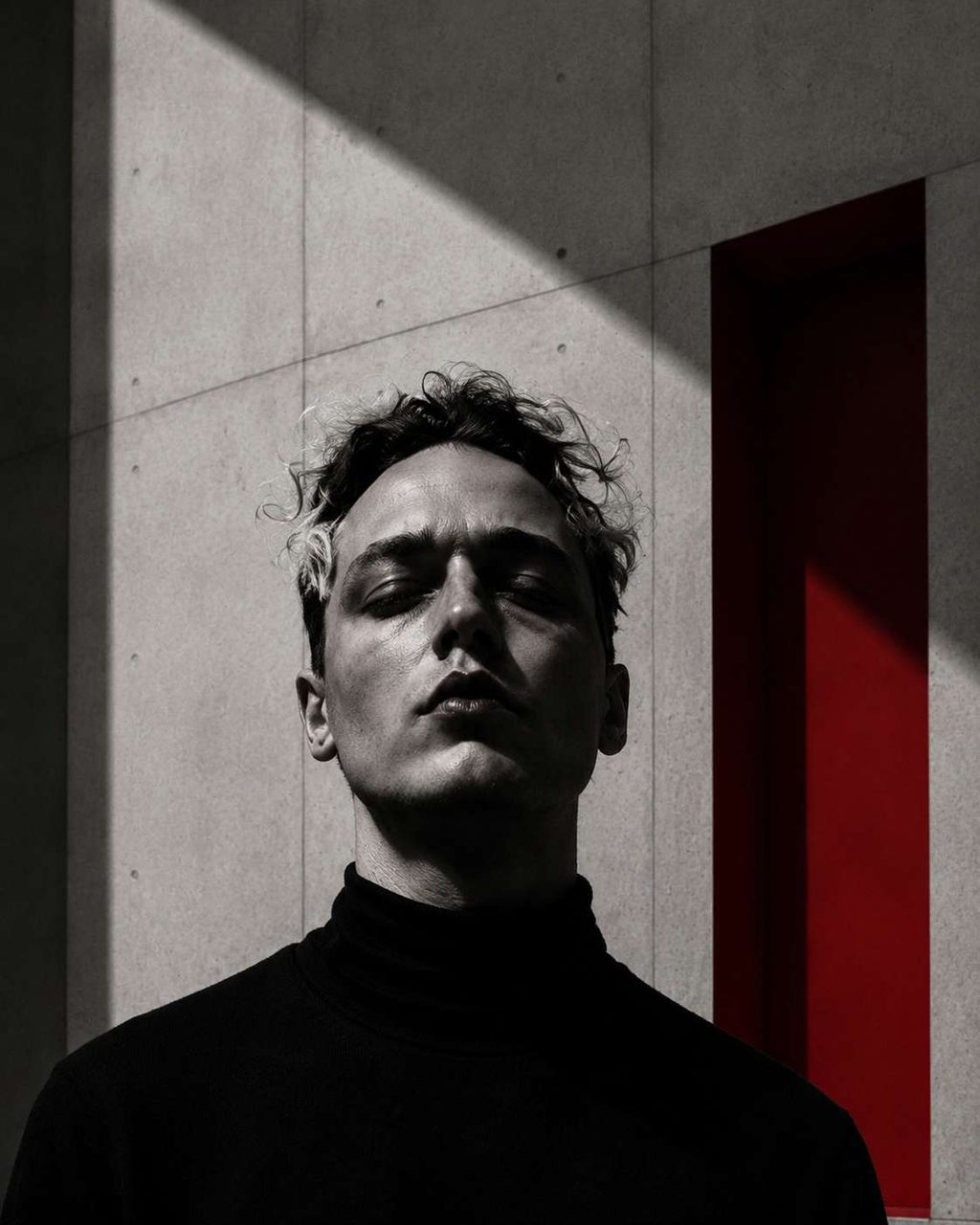 A portrait in a concrete interior, one red plane behind the figure.