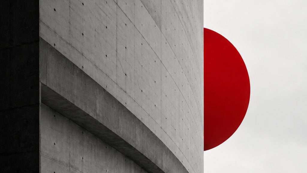 A curving concrete wall under a pale sky, a single red sphere rising behind it.